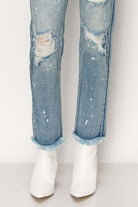 High rise distressed straight fray hem jeans with bleach effect, styled with white boots.