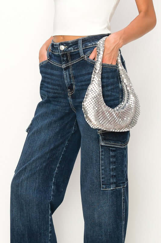 Woman wearing high rise wide jeans with a silver handbag, showcasing stylish casual fashion.