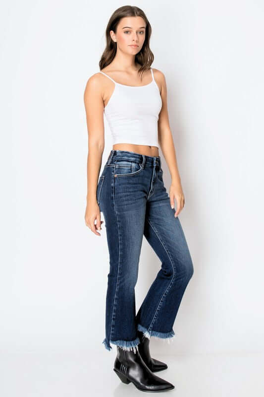 Woman wearing Corset High Rise Crop Flare Jeans with tummy control panel, styled casually with a white tank top and black boots.