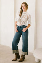 Woman wearing tummy control high rise cuffed wide leg jeans with lace top, highlighting comfortable fit and flattering silhouette.