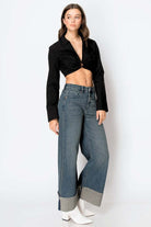 Woman wearing tummy control high rise wide leg jeans with cuffed detailing and a black crop top, showcasing a stylish silhouette.